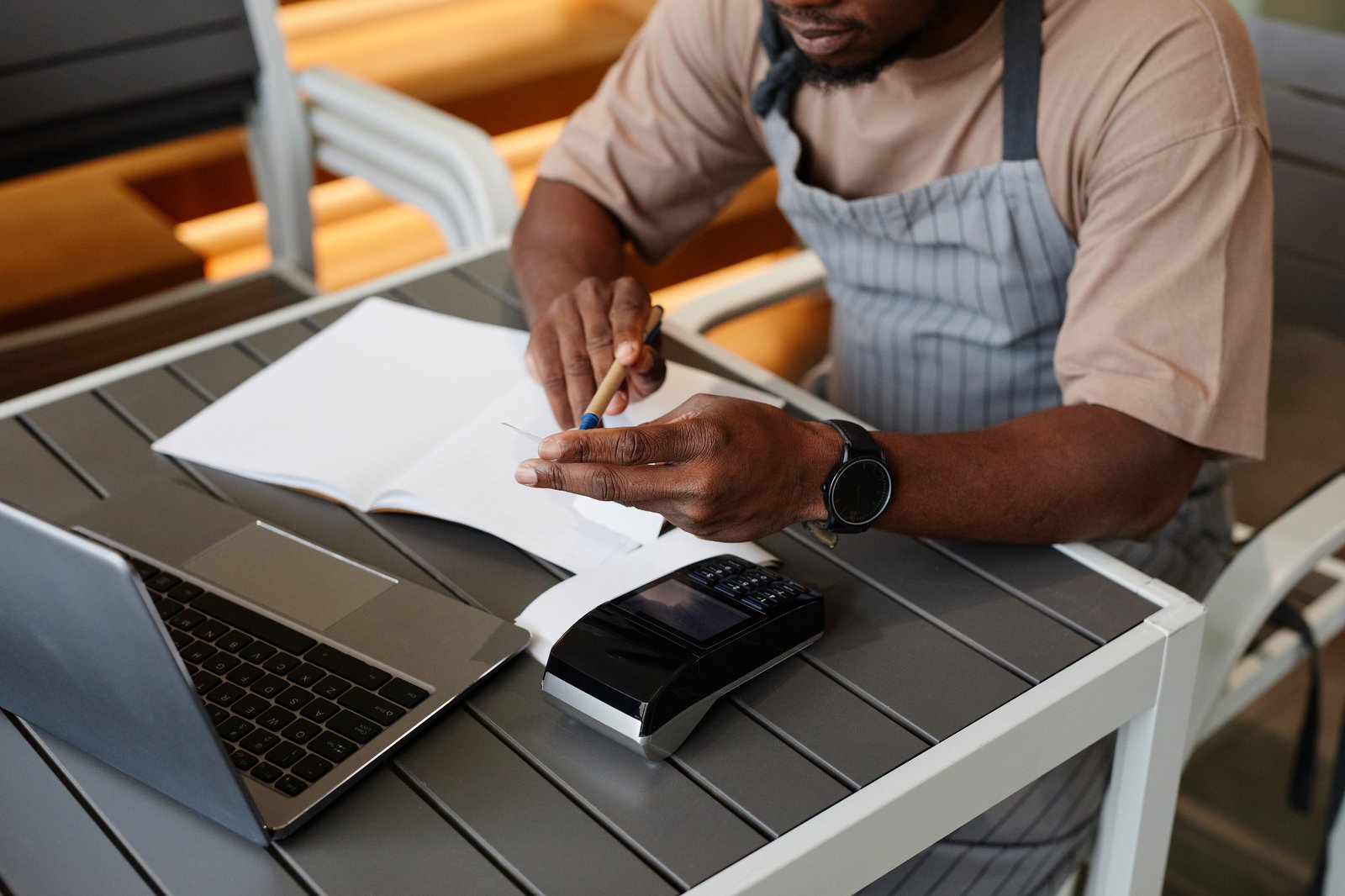 Landscaping business owner reviewing equipment costs on paper and laptop