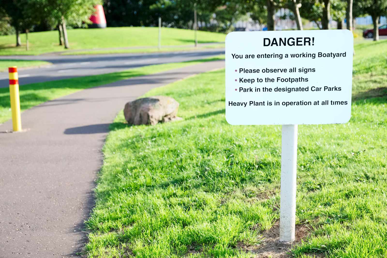 Safety warning sign posted on a lawn where automated machinery operates