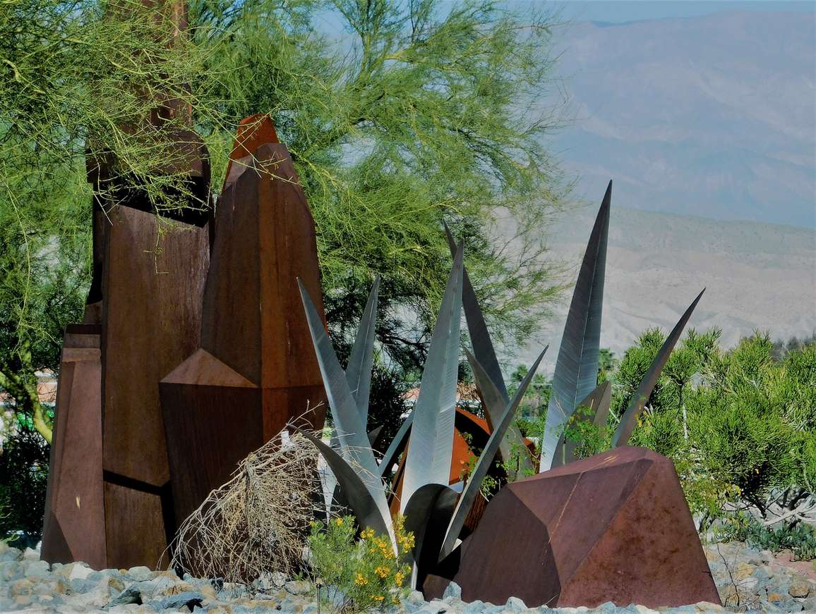 Contemporary metal sculpture installed among the planting in a garden