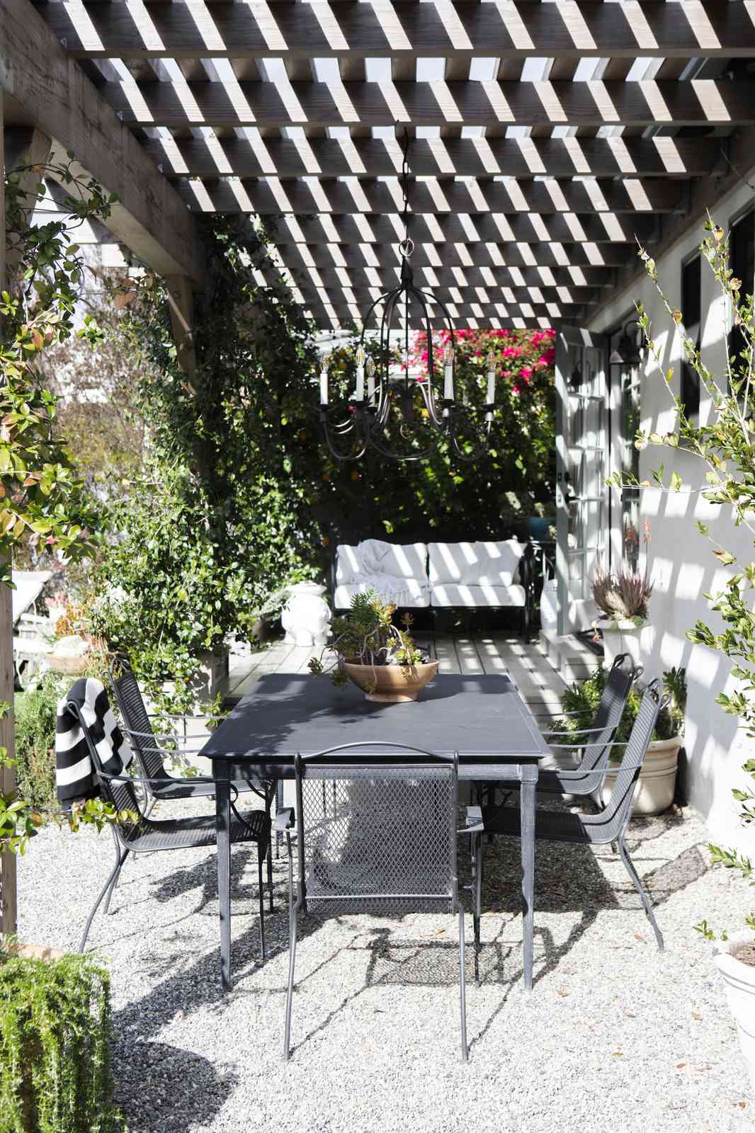 Outdoor dining table set beneath a wooden pergola in a garden