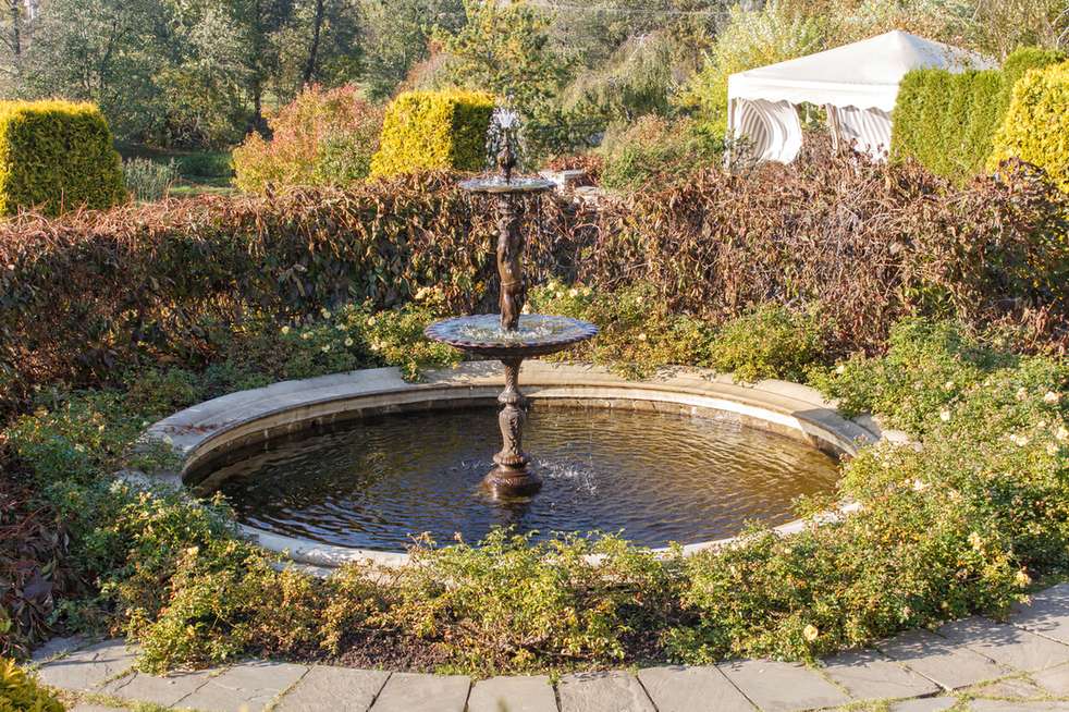 Multi-tiered stone fountain used as a central water feature in a garden